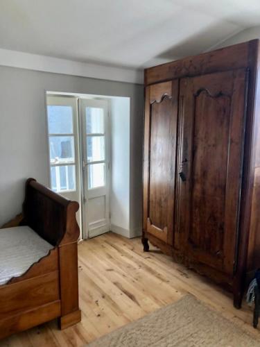 a bedroom with a bed and a large wooden cabinet at Eulalie ,maison de village avec jardin in Saint-Aulaye
