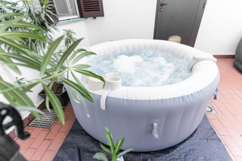 a large white bath tub on a patio with plants at Zen Retreat per Coppie con Jacuzzi - Dehor e Garage Privato - Check in Automatico 24 7 in Casale Monferrato