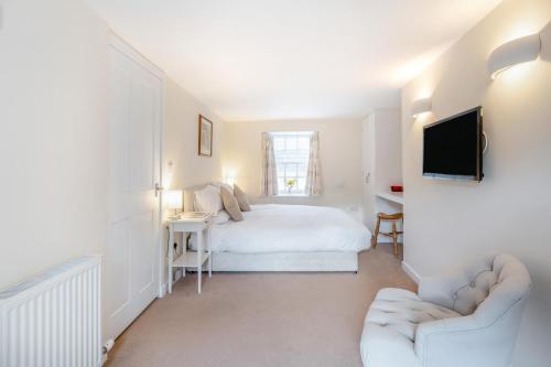 a white bedroom with a bed and a tv at Artist Cottage - Kirkudbright in Kirkcudbright