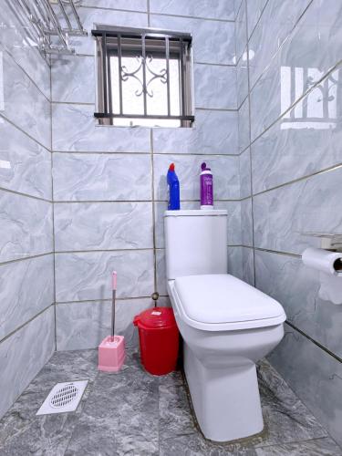 a bathroom with a white toilet and a window at Sunbeam BnB Bweyogerere in Kampala