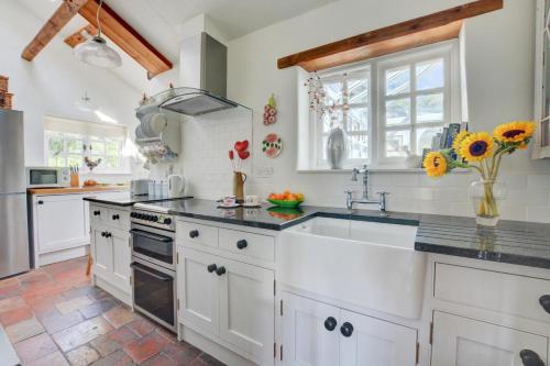 a kitchen with white cabinets and a sink at Old Beams in Stiffkey