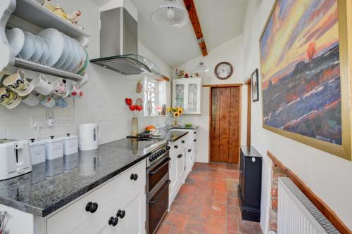 a kitchen with white cabinets and a counter top at Old Beams in Stiffkey