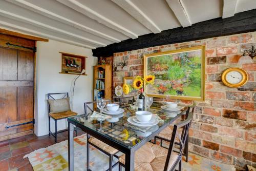 a dining room with a table and a brick wall at Old Beams in Stiffkey