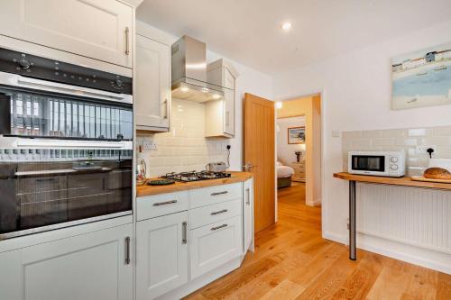 a kitchen with white cabinets and a stove top oven at Sunbeam in Snettisham