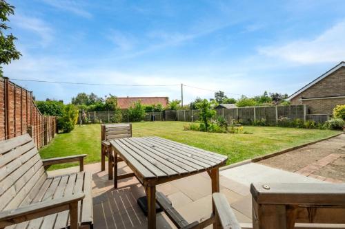 a patio with two benches and a wooden table at Sunbeam in Snettisham