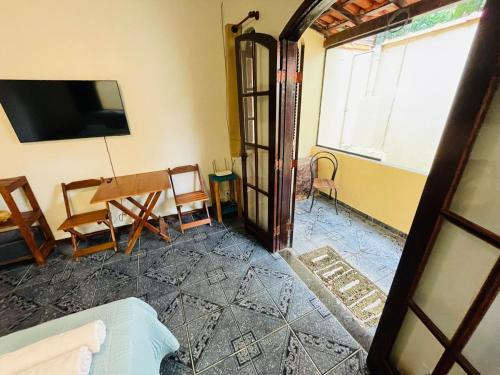 a living room with a tv and a table and chairs at Casa na Vila do Abraão - Ilha Grande in Angra dos Reis