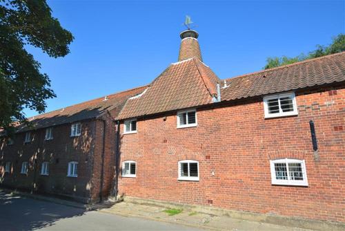 a large red brick building with a chimney on it at The Maltings in Ludham