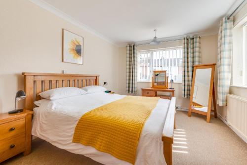 a bedroom with a large bed with a yellow blanket at Sunsette in Reydon