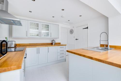 a kitchen with white cabinets and a wooden counter top at Anchors Aweigh in Southwold