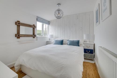a white bedroom with a large bed with blue pillows at Anchors Aweigh in Southwold