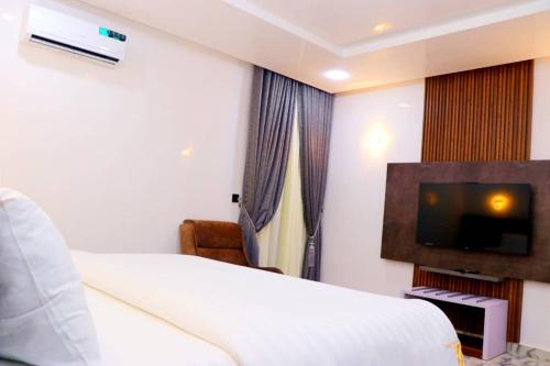 a hotel room with a bed and a flat screen tv at See2ru Burj Apartment and Lounge in Abuja