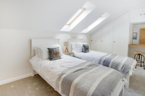 two beds in a room with white walls at Swallows Roost in Sudbury