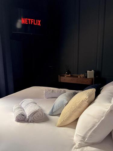a bed with white pillows and aadobe at Suite Romantique, hyper centre in Caen