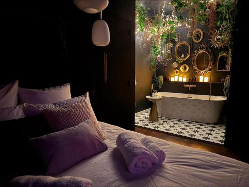 a bedroom with a tub and a bed with purple pillows at Suite Romantique, hyper centre in Caen