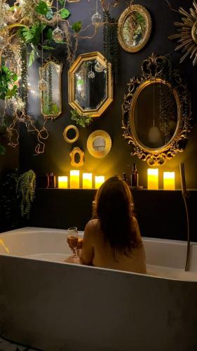 a woman sitting in a bath tub with a glass of wine at Suite Romantique, hyper centre in Caen