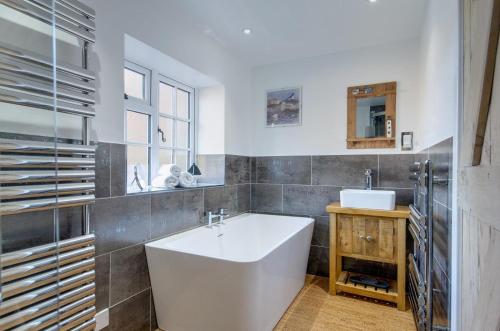 ein Badezimmer mit einer weißen Badewanne und einem Waschbecken in der Unterkunft Town Yard Cottage in Cley next the Sea