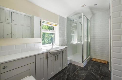 a white bathroom with a sink and a shower at Barn Meadow Cottage in Yoxford