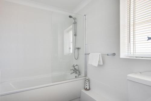 a white bathroom with a shower and a sink at Church Meadow Cottage in Trimingham