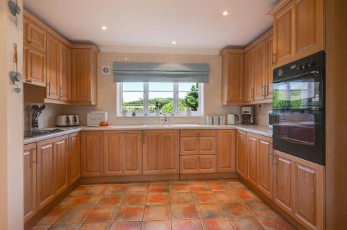 a large kitchen with wooden cabinets and a window at Church Meadow Cottage in Trimingham