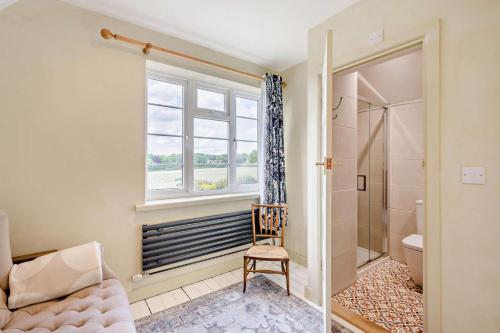 a bathroom with a window and a chair and a shower at Oak View - Holbrook in Holbrook