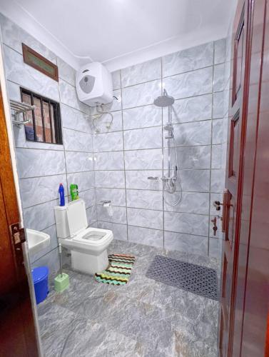 a bathroom with a shower and a toilet and a sink at Sunbeam Homes Kampala in Kampala