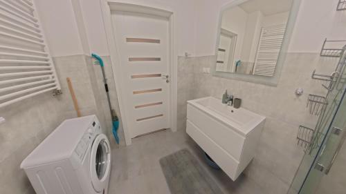 une salle de bains avec lave-linge et lavabo dans l'établissement GARDENIA Apartament Przy Plaży 17, à Dziwnów