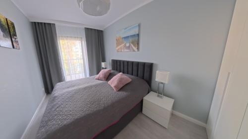 - une chambre avec un lit doté d'oreillers roses et d'une fenêtre dans l'établissement GARDENIA Apartament Przy Plaży 17, à Dziwnów