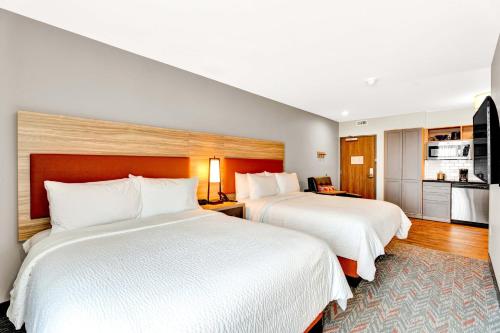 a hotel room with two beds and a kitchen at Candlewood Suites - Detroit - Auburn Hills by IHG in Auburn Hills