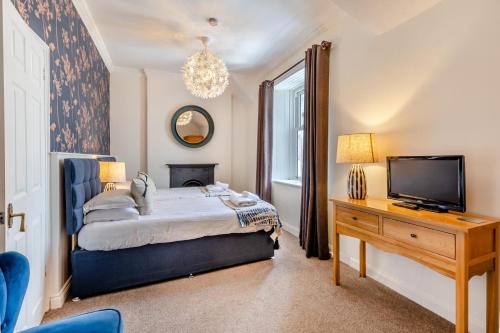 a bedroom with a bed and a tv and a desk at The Greenhouse in Bamburgh