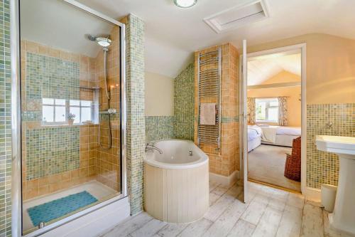 a bathroom with a tub and a shower and a sink at Coach House Cottage in Wickham Market