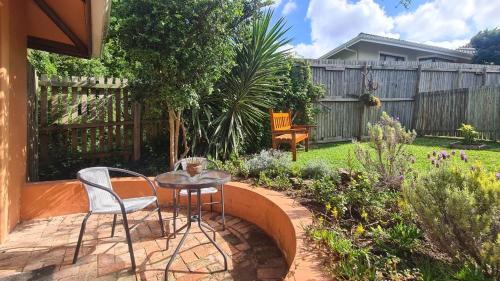a patio with a table and chairs in a garden at Firefly Cottage: Cosi nest tucked away in garden in Kenton on Sea