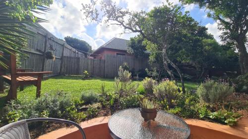 a patio with a glass table in a garden at Firefly Cottage: Cosi nest tucked away in garden in Kenton on Sea
