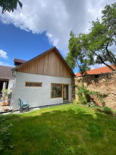 a house with a stone wall and a grass yard at Waldquartier Palazzo Tiefenbach in Kautzen