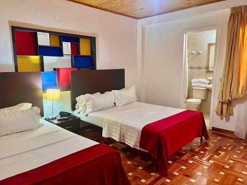 a bedroom with two beds and a colorful painting on the wall at Casa Coliving 121 in Bogotá