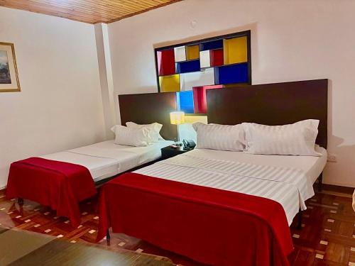 two beds in a room with a painting on the wall at Casa Coliving 121 in Bogotá