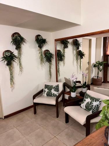 a living room with two chairs and plants on the wall at Hotel Raices Esturion in Puerto Iguazú
