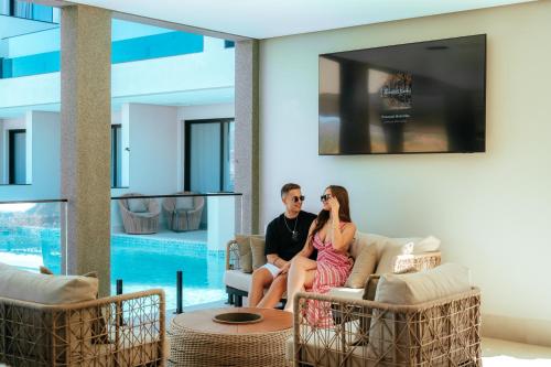 a man and woman sitting on a couch in a living room at Collegare Hotel in Capitólio