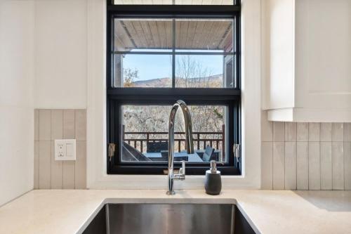 une cuisine avec un évier et une fenêtre dans l'établissement Les Eaux Luxe Mountain View Condo Private Sauna, à Mont-Tremblant