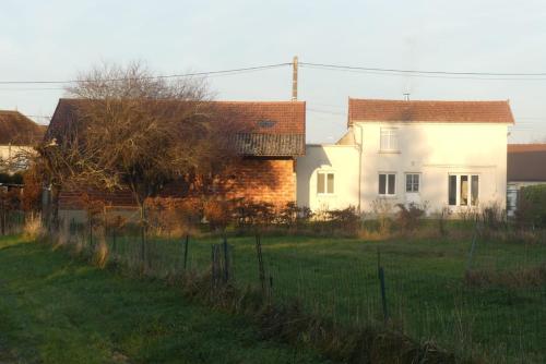 a white house with a fence in a field at La maison du verger in Magny-Fouchard