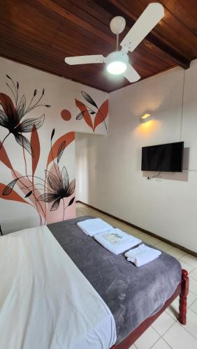 a bedroom with a bed with a tv on the wall at Ka'a Guest House in Ubatuba