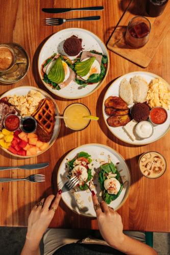 una persona sentada en una mesa con platos de comida en Puro Surf Hotel & Performance Academy, en El Zonte