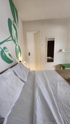 a bedroom with a white bed with a painting on the wall at Ka'a Guest House in Ubatuba
