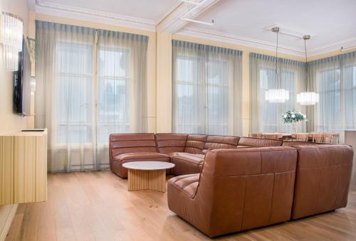 a living room with brown leather furniture and windows at Les Lofts du Pont - Par Les Lofts Vieux-Québec in Quebec City