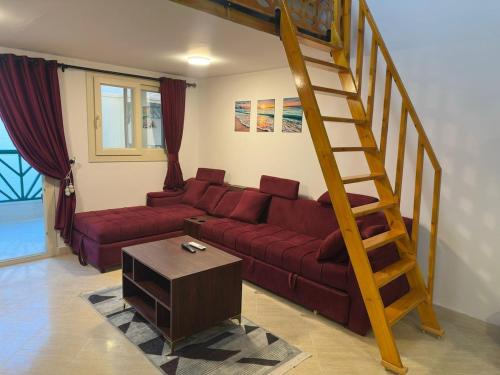 マルサー・アラムにあるSeaside Modern Loft Chalet in Marsa Alamのリビングルーム(赤いソファ、木製の階段付)