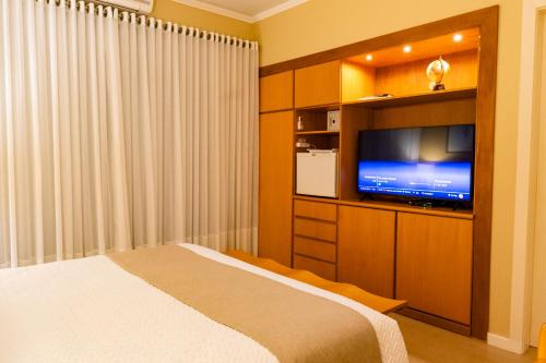 a bedroom with a bed and a flat screen tv at Hotel Pousada da Neve in Nova Petrópolis