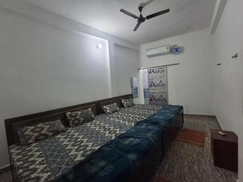 a bedroom with a bed with a ceiling fan at Shree Venkateshwar dham Atithi bhawan in Naimishāranya