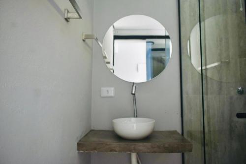 a bathroom with a mirror and a bowl on a counter at Residencial Solar do Pescador in São Sebastião