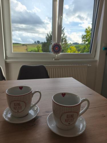 two cups on a table in front of a window at Kleine Auszeit Eifel mit Dachterrasse in Nettersheim