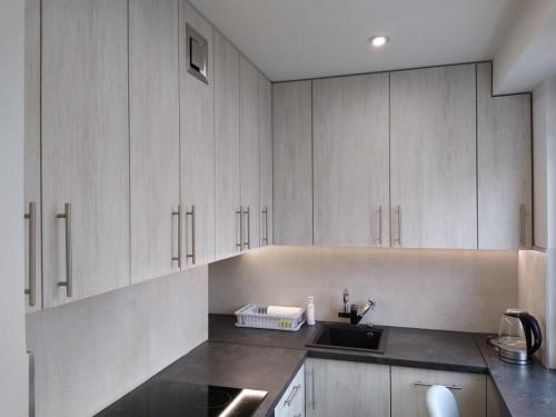 a kitchen with white cabinets and a sink at Apartament Bocianek in Kielce