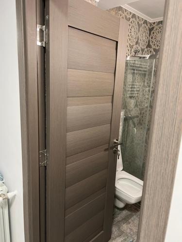 a bathroom with a toilet and a wooden door at Central Luxury Apartament in Tulcea